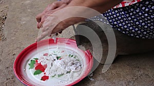 Elderly woman hand scraping coconut out of a fresh raw coconut on tray , prepared for Thai cooking