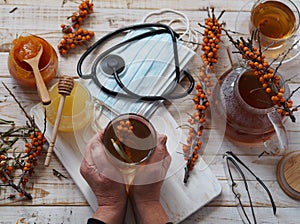 An elderly woman is hands hold a cup of sea buckthorn tea. The concept of protecting and treating flu and colds with folk remedies