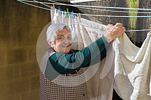 Elderly woman hanging out the washing on the terrace
