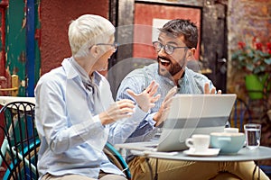 An elderly woman has an interesting talk with her young male friend while spending free time at bar`s garden together. Leisure,