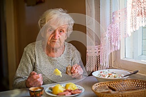 Elderly woman is having dinner sitting at the table alone.