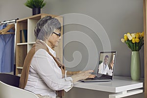 Elderly woman having online consultation doctor on laptop sitting at home
