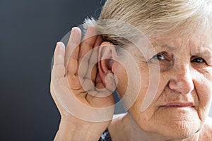 Elderly woman with hearing loss on grey background. Age related