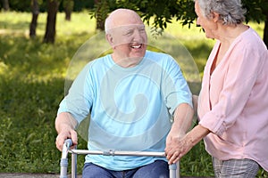 Elderly woman helping her husband with walking frame