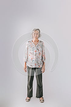 Elderly woman in her 80's with Gray hair standing isolated on a white backdrop