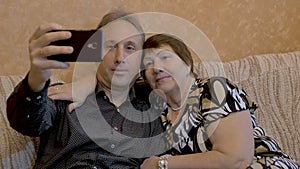 An elderly woman and her adult son are photographed on a smartphone.