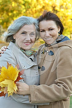 An elderly woman with her daughter in the park in autumn.