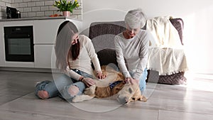 Elderly Woman With Her Granddaughter Gently Stroking Adorable Golden Retriever Dog