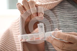 Elderly woman holding container with different pills, closeup