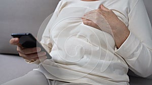 Elderly woman holding hand on chest, calling ambulance, first aid, health care