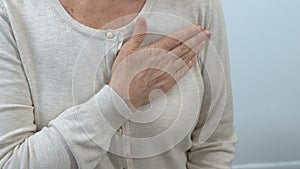 Elderly woman holding hand on chest, health examination, doctor appointment