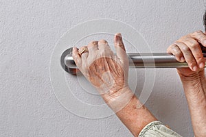 Elderly woman holding on handrail for safety walk