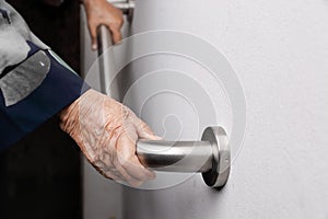 Elderly woman holding on handrail for safety walk