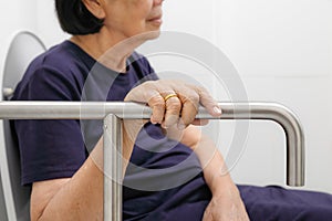 Elderly woman holding on handrail in toilet.