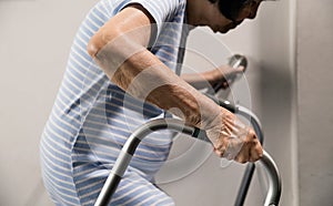 Elderly woman holding on handrail and walker for safety