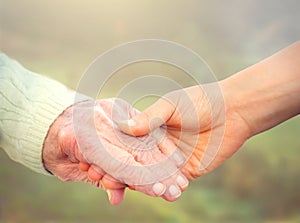 Elderly woman holding hands with young caregiver