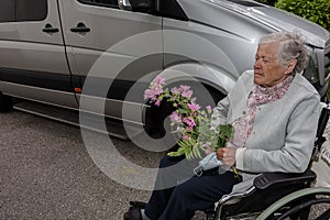 Elderly woman holding a medical mask with flower Concept of a disabled person in a wheelchair transporting patients in a