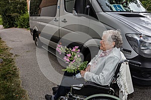 Elderly woman holding a medical mask with flower Concept of a disabled person in a wheelchair transporting patients in a