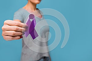 Elderly woman holding purple ribbon awareness w copy space. Symbol is used to raise awareness for Alzheimer`s disease