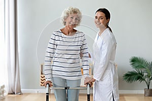 Elderly woman holding rollator feels satisfied after therapy with physiotherapist
