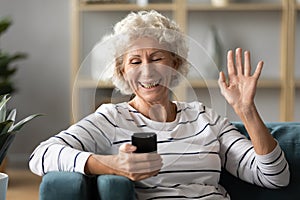 Elderly woman holding smartphone wave hand having videocall