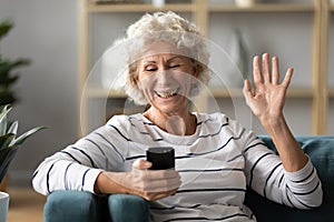 Elderly woman holding smartphone wave hand having videocall photo