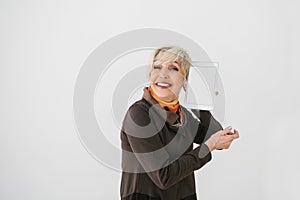 Elderly woman holding a tablet with an empty white screen and smiling. The older generation and modern technology.