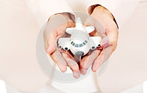 Elderly woman holding a toy plane on open plams