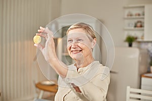 An elderly woman holds a bitcoin coin in her hand and smiles. Senior citizen happy life concept
