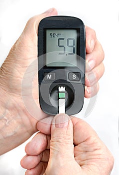 An elderly woman holds a glucometer in her hands and wants to do a blood test for sugar