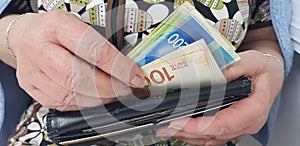 Elderly woman holds in hands israeli cash money