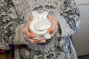 Elderly woman holds a piggy bank in her hands, concept of saving money for retirement