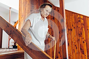 Elderly woman at home using a cane to get down the stairs