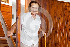 Elderly woman at home using a cane to get down the stairs