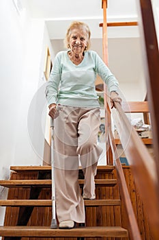 Elderly woman at home using a cane to get down the stairs