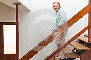 Elderly woman at home using a cane to get down the stairs