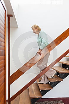 Elderly woman at home using a cane to get down the stairs