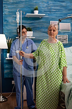 Elderly woman in hospital room standing up after surgery