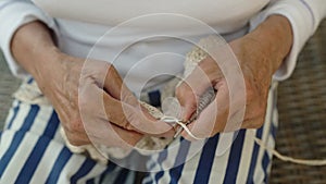 An elderly woman knits on knitting needles, portrait and close-up.