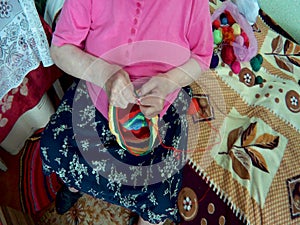 elderly woman knits a product