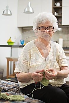 Elderly woman knitting at home