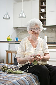 Elderly woman knitting at home