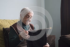 Elderly woman knitting at home