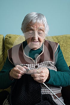 Elderly woman knitting at home