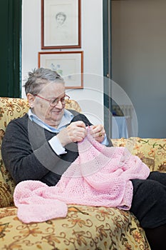 Elderly woman knitting pink wool portrait