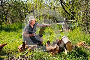 Elderly woman with laptop and chickens in village