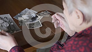 An elderly woman looks at the old family photographs - Recalls memories