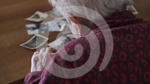 An elderly woman looks at the old family photographs - Recalls memories