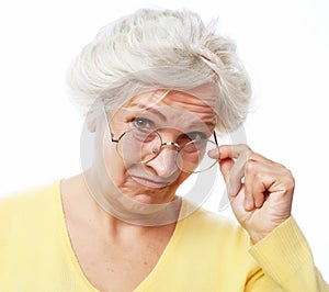 An elderly woman looks skeptically over her glasses.