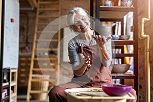 Elderly woman making ceramic work with potter`s wheel